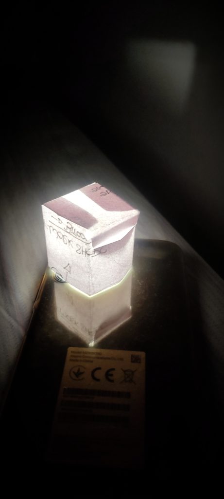 Completed DIY lamp cube emitting a soft glow from within, showcasing intricate paper folds and elegant design